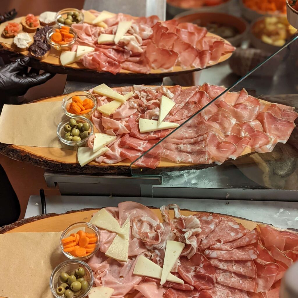 Three platters with many different types of Tuscan hams and cheeses